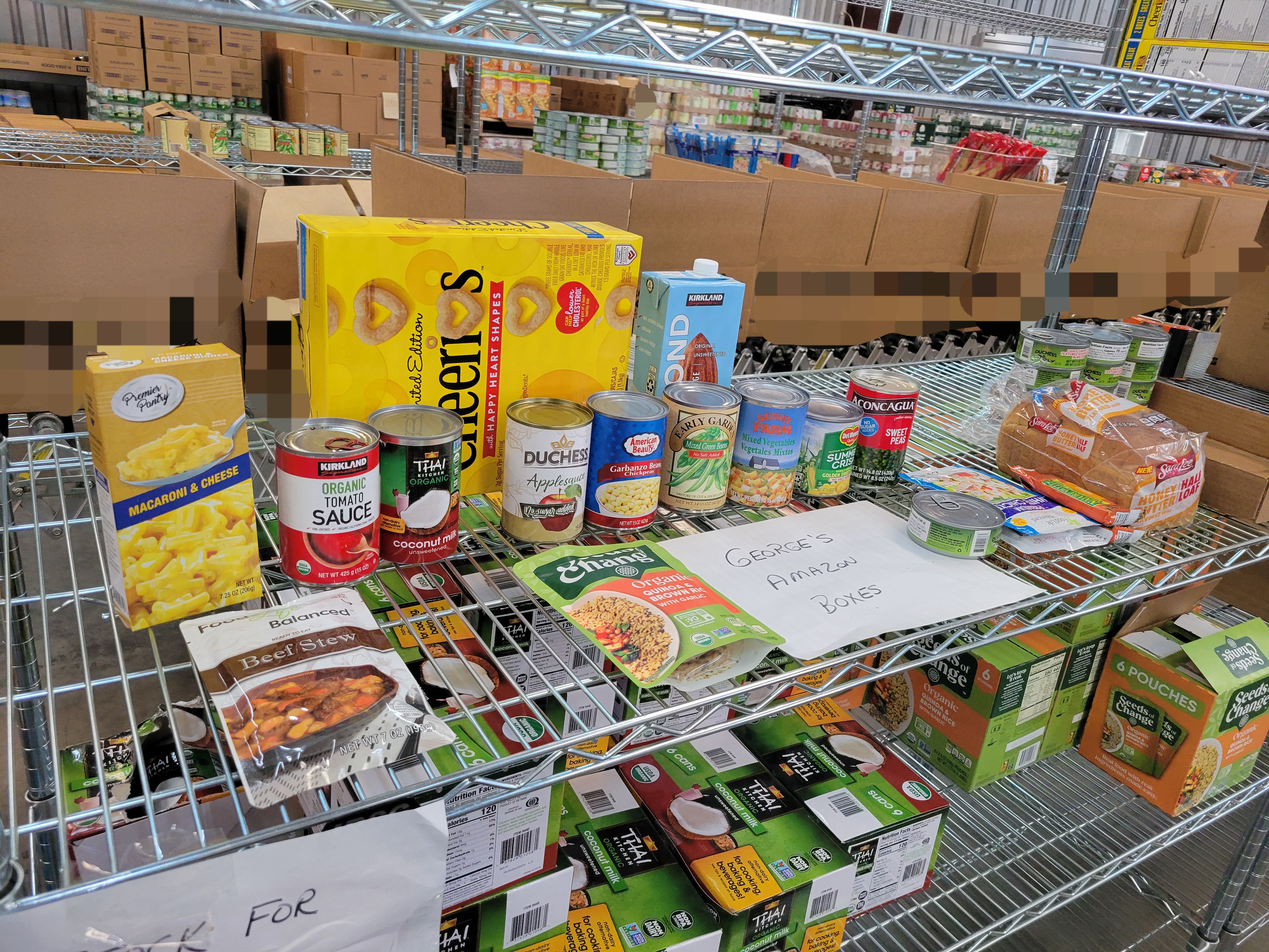 Dry goods on shelf with boxes of canned coconut milk under it and row of boxes behind it.